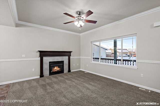 unfurnished living room with crown molding, carpet floors, a tile fireplace, and ceiling fan