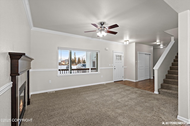 unfurnished living room featuring ceiling fan, ornamental molding, and dark carpet