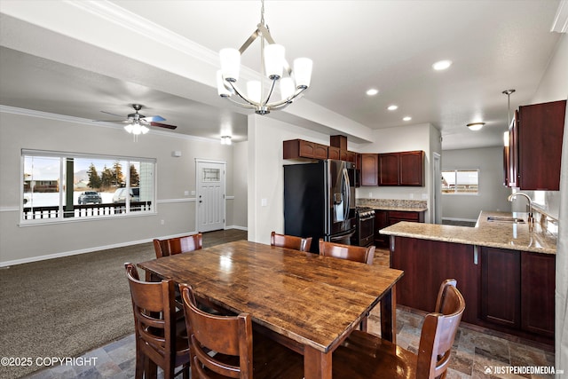 carpeted dining space with sink, ceiling fan with notable chandelier, and ornamental molding