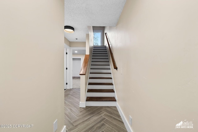 stairs featuring a textured ceiling and parquet floors