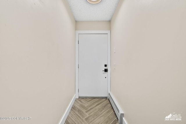 doorway with a baseboard heating unit and a textured ceiling