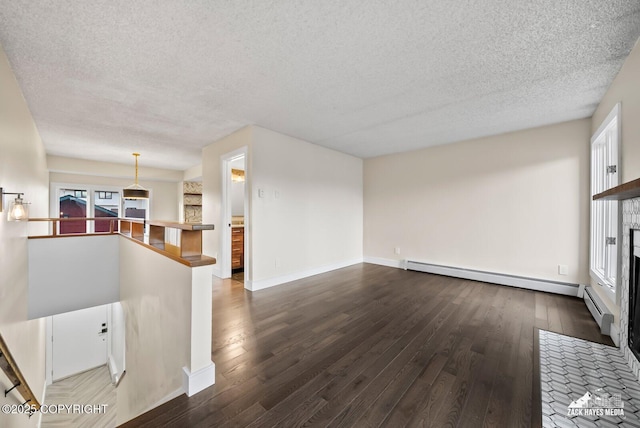 unfurnished living room with a baseboard heating unit, dark wood-type flooring, a tiled fireplace, and a textured ceiling