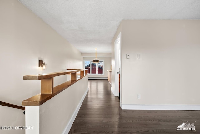 hall with a textured ceiling, dark wood-type flooring, and a baseboard heating unit