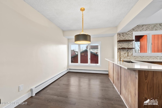 unfurnished dining area featuring sink, a textured ceiling, and baseboard heating