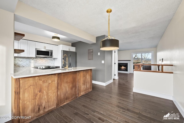 kitchen with kitchen peninsula, pendant lighting, stainless steel appliances, tasteful backsplash, and white cabinetry