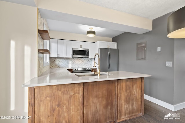 kitchen featuring kitchen peninsula, stainless steel appliances, backsplash, white cabinets, and sink