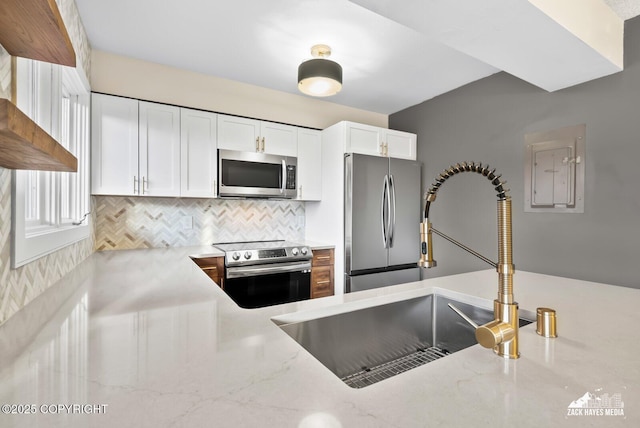 kitchen featuring light stone countertops, stainless steel appliances, tasteful backsplash, white cabinets, and sink