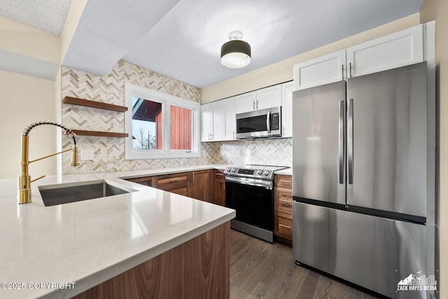 kitchen featuring appliances with stainless steel finishes, dark hardwood / wood-style flooring, white cabinets, backsplash, and sink