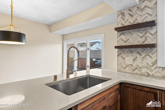 kitchen with sink, a textured ceiling, and hanging light fixtures