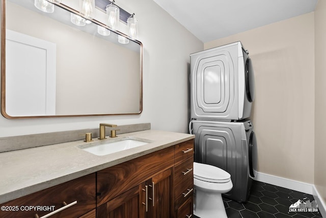 bathroom featuring toilet, vanity, tile patterned floors, and stacked washer / drying machine