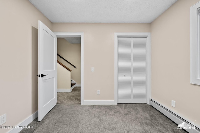 unfurnished bedroom featuring a textured ceiling, light colored carpet, a baseboard radiator, and a closet