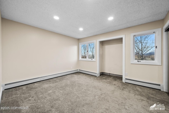 unfurnished bedroom with a textured ceiling, baseboard heating, and carpet