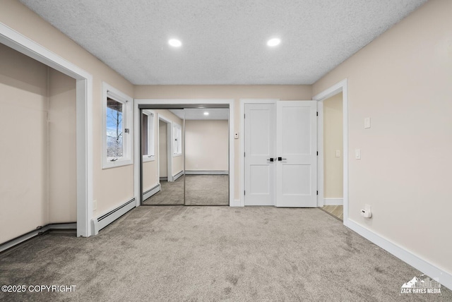 hall with a textured ceiling, baseboard heating, and carpet