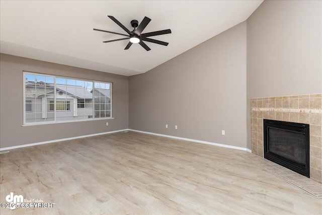 unfurnished living room with vaulted ceiling, ceiling fan, light hardwood / wood-style flooring, and a tiled fireplace