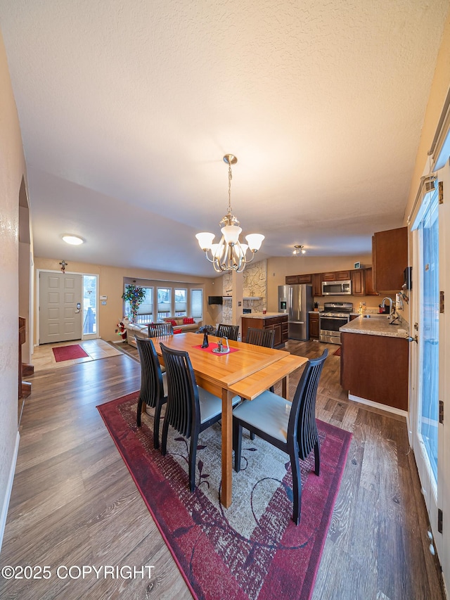 dining area with an inviting chandelier, sink, and dark wood-type flooring