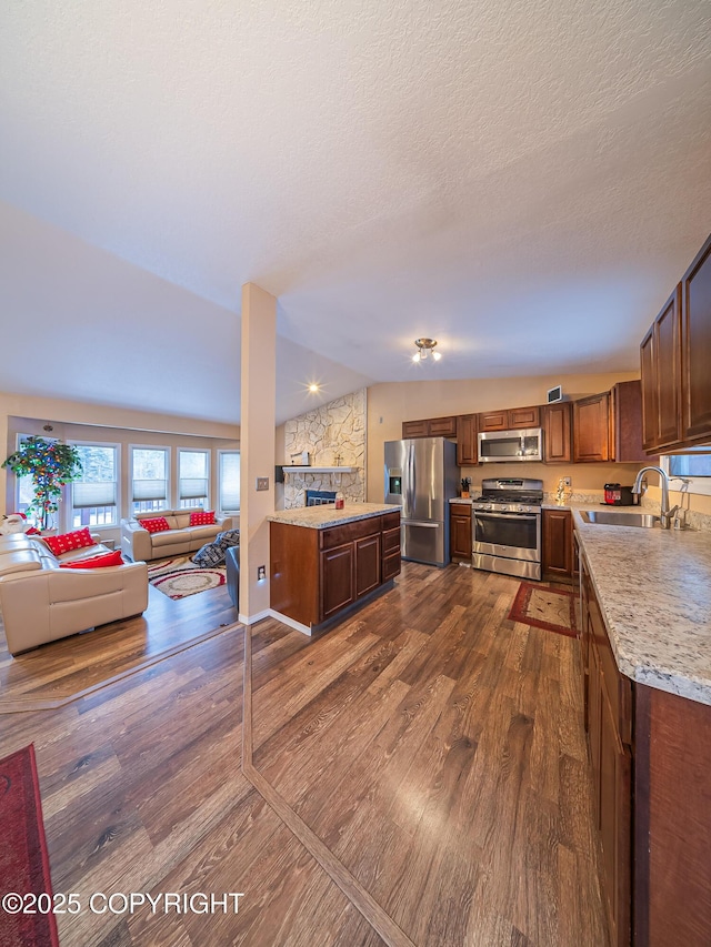 kitchen with lofted ceiling, sink, stainless steel appliances, dark hardwood / wood-style floors, and a textured ceiling