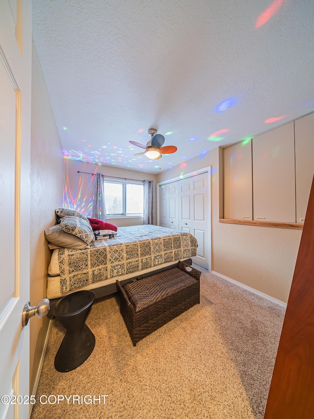 bedroom featuring carpet flooring, a textured ceiling, ceiling fan, and a closet