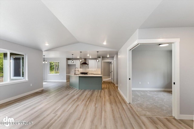 unfurnished living room with light wood-type flooring, vaulted ceiling, and sink