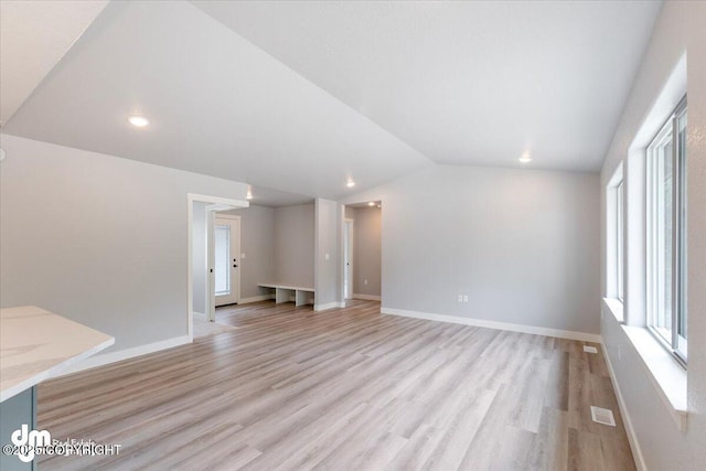 unfurnished living room with light hardwood / wood-style flooring, lofted ceiling, and plenty of natural light