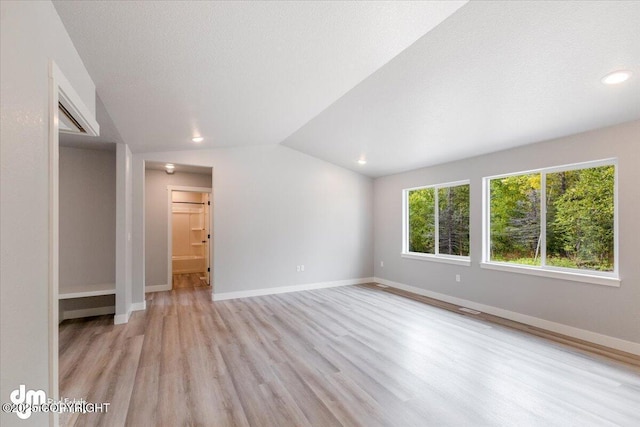 interior space with a textured ceiling, light hardwood / wood-style flooring, and vaulted ceiling