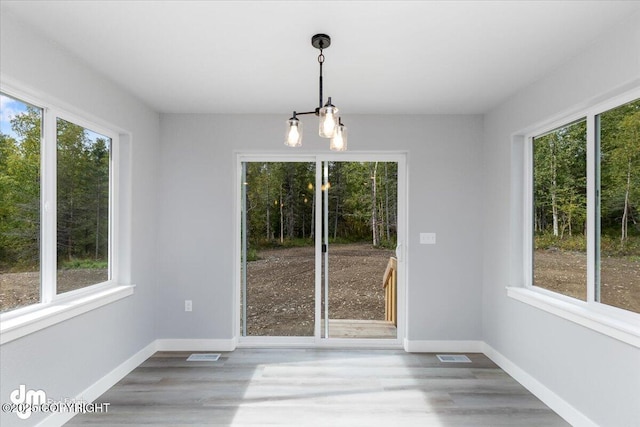 unfurnished dining area featuring hardwood / wood-style floors and an inviting chandelier