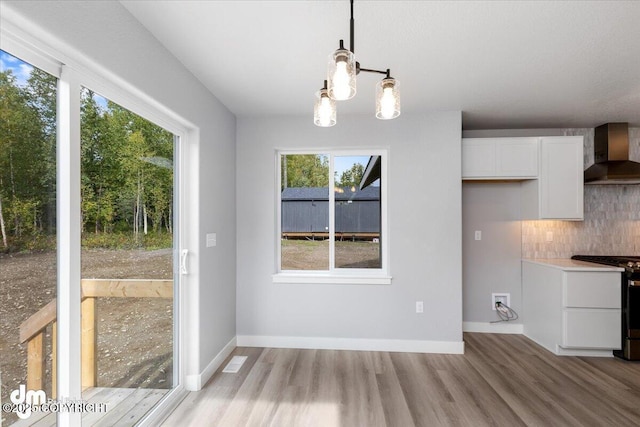 unfurnished dining area with a notable chandelier and light hardwood / wood-style flooring