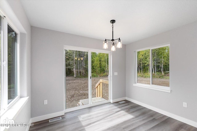 unfurnished dining area featuring a notable chandelier and hardwood / wood-style floors