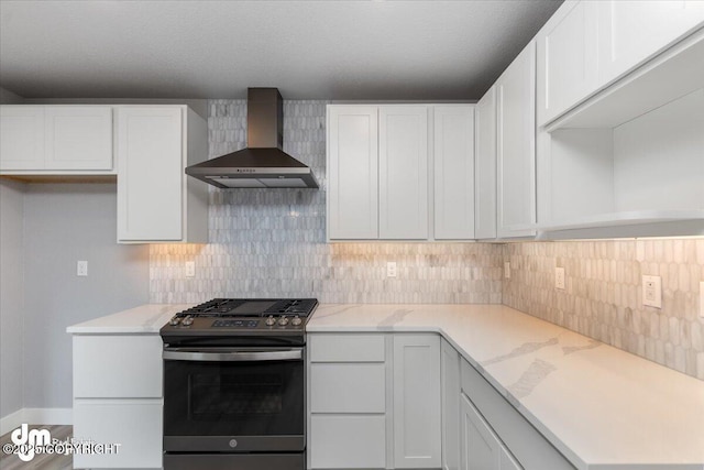 kitchen with white cabinets, stainless steel gas range oven, and wall chimney exhaust hood