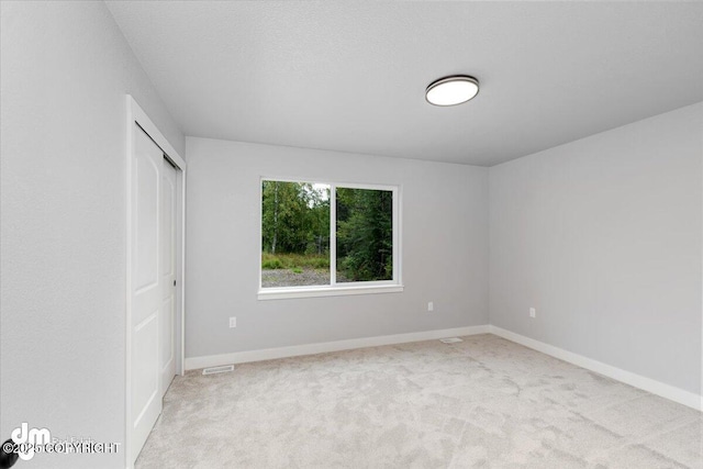 unfurnished bedroom featuring a closet and light carpet