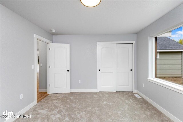 unfurnished bedroom with a closet, multiple windows, and light colored carpet