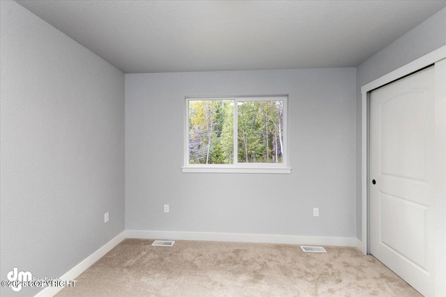 unfurnished bedroom featuring a closet and light carpet