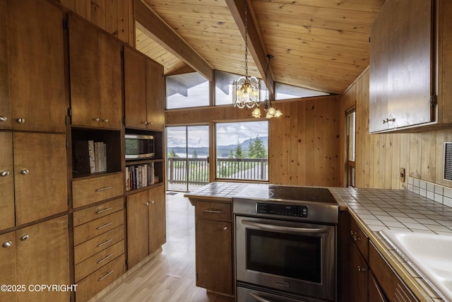 kitchen with wall oven, a chandelier, tile countertops, and pendant lighting