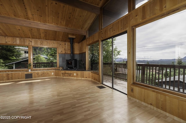 unfurnished sunroom featuring lofted ceiling with beams, a wood stove, and wood ceiling