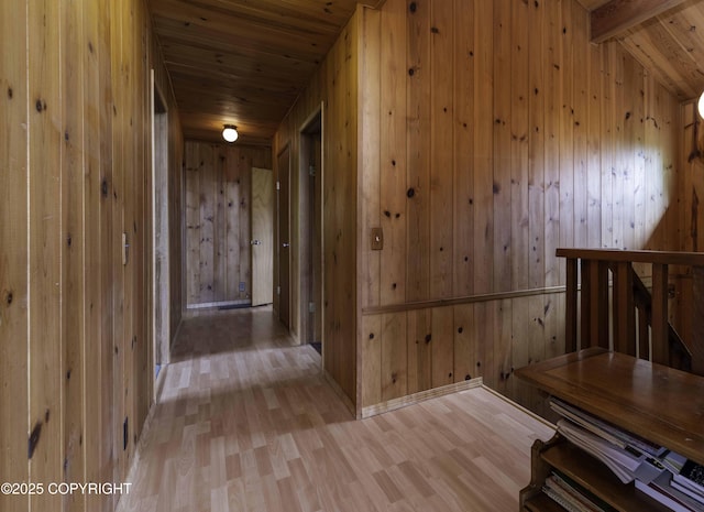 hallway with beamed ceiling, light hardwood / wood-style floors, wood ceiling, and wooden walls