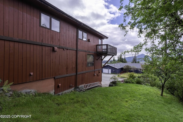 view of side of property with a balcony and a yard