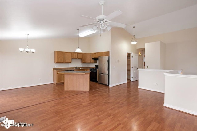 kitchen with hanging light fixtures, a center island, dark hardwood / wood-style flooring, stainless steel refrigerator, and black range with gas cooktop