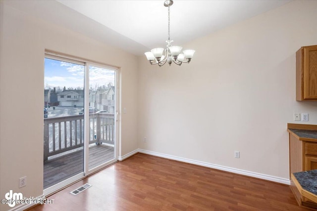 unfurnished dining area with hardwood / wood-style flooring and a notable chandelier