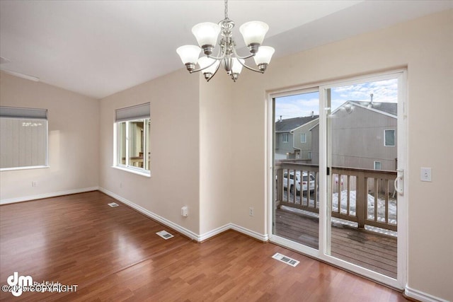 unfurnished dining area with lofted ceiling, wood-type flooring, and a chandelier