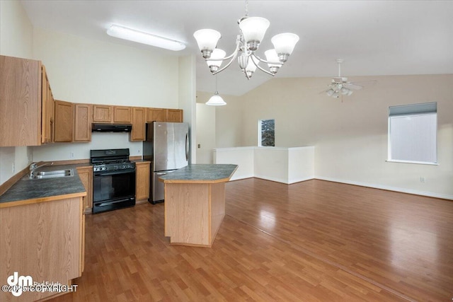 kitchen with black gas range oven, stainless steel fridge, a kitchen island, sink, and decorative light fixtures