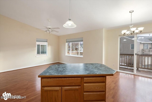 kitchen with dark hardwood / wood-style flooring, a center island, ceiling fan with notable chandelier, and hanging light fixtures