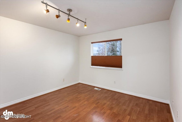 spare room featuring hardwood / wood-style flooring and rail lighting