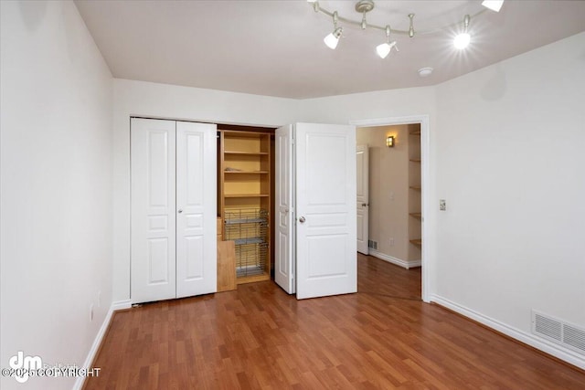 unfurnished bedroom with a closet, hardwood / wood-style floors, and a spacious closet