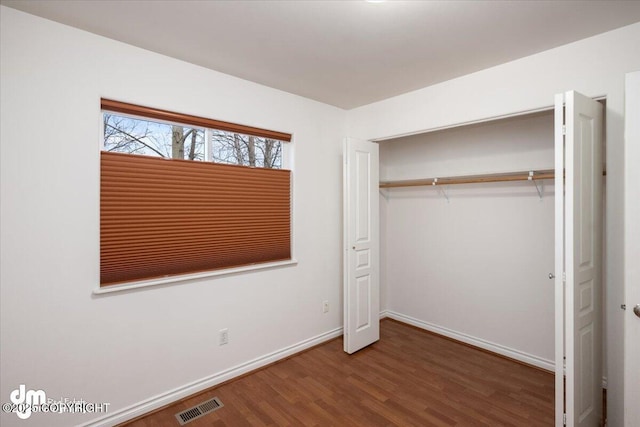 unfurnished bedroom featuring a closet and dark hardwood / wood-style flooring