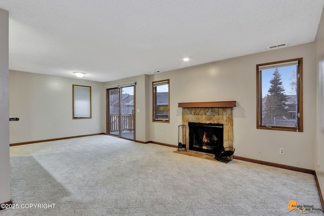 unfurnished living room with a fireplace, a healthy amount of sunlight, and light colored carpet