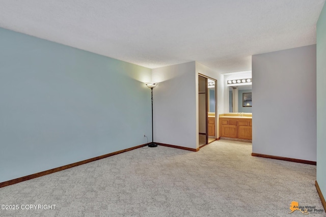 unfurnished bedroom with ensuite bathroom and light carpet