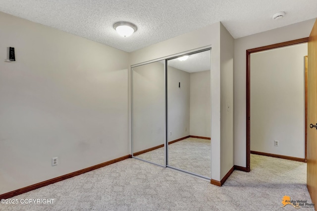 unfurnished bedroom featuring a textured ceiling, light colored carpet, and a closet