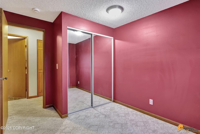 unfurnished bedroom with a textured ceiling, light colored carpet, and a closet