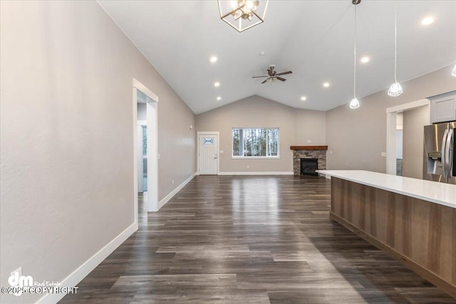 unfurnished living room featuring dark wood-type flooring, ceiling fan, a fireplace, and vaulted ceiling