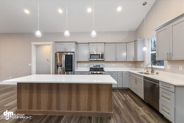 kitchen featuring pendant lighting, stainless steel appliances, sink, and a kitchen island