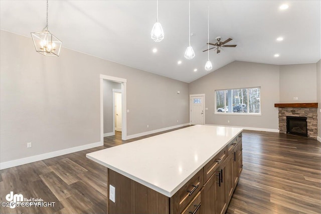 kitchen featuring pendant lighting, lofted ceiling, dark wood-type flooring, a fireplace, and a kitchen island